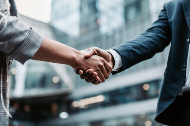 Meeting success. Two business persons shaking hands standing outside Meeting success. Two business persons shaking hands standing outside